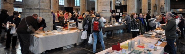 bezoekers van de beurs kijken naar boeken uitgestald op tafels