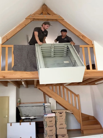 twee mannen staan op een zolder en houden een zware kast vast